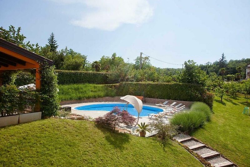 Una piscina con mobili da esterno circondata da un paesaggio naturale.