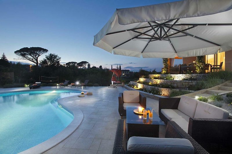 Una proprietà con piscina, mobili da esterno e ombrellone in una zona residenziale vicino al mare.