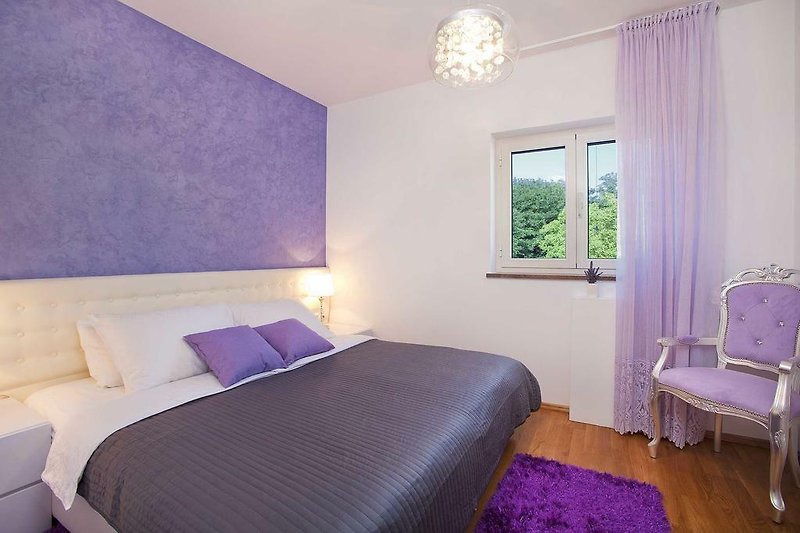 Una camera da letto con arredamento viola e finestra in legno.