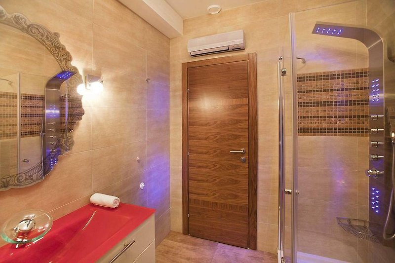 Un bagno moderno con mobili eleganti, specchio e illuminazione raffinata.