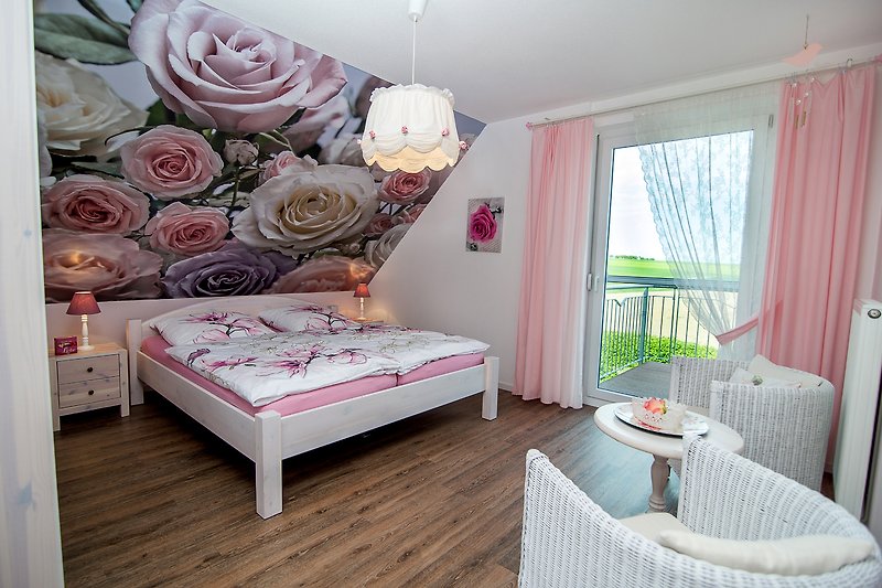 Gemütliches Schlafzimmer mit rosa Bettwäsche und blumiger Dekoration.