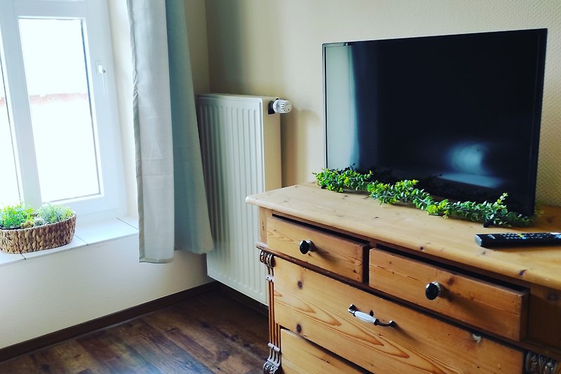 Gemütliches Wohnzimmer mit Holzmöbeln und grünen Pflanzen.