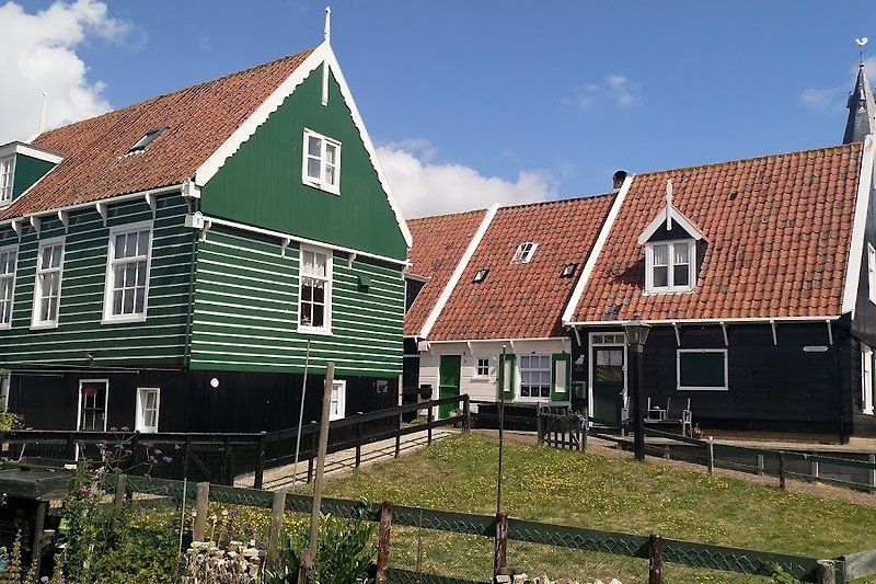 Gemütliches Cottage mit Holzfassade, grünem Gras und blauem Himmel. Marken Insel.