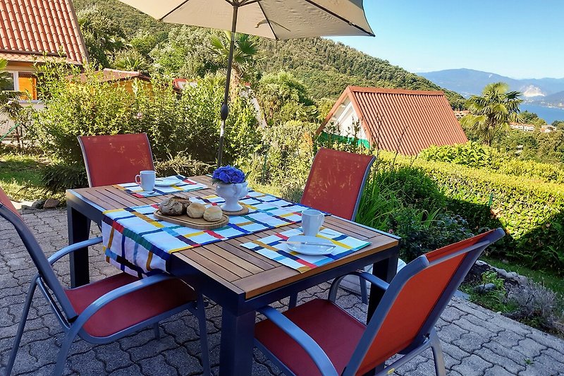 Gemütliche Terrasse mit Tisch, Stühlen und Sonnenschirm.