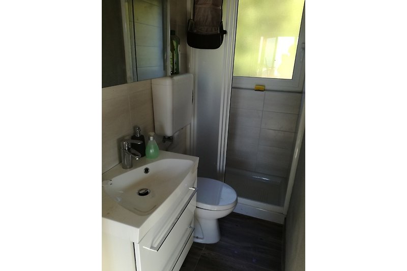 Gemütliches Badezimmer mit lila Akzenten, Holzschrank und Spiegel.