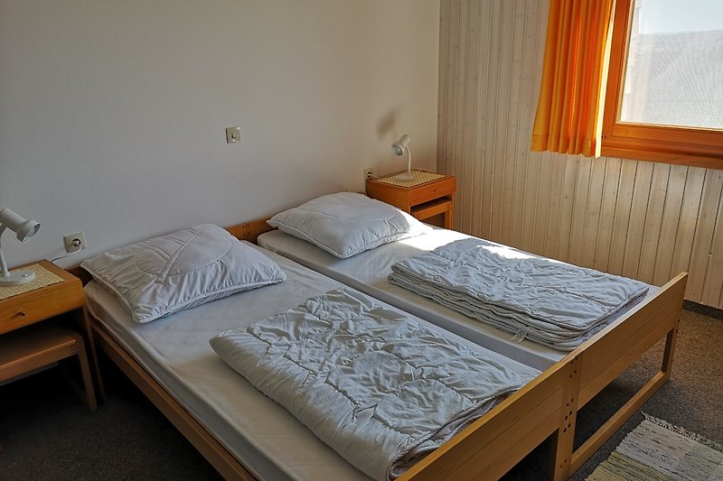 Gemütliches Schlafzimmer mit Holzmöbeln und bequemen Betten sowie einem Kinderbett.