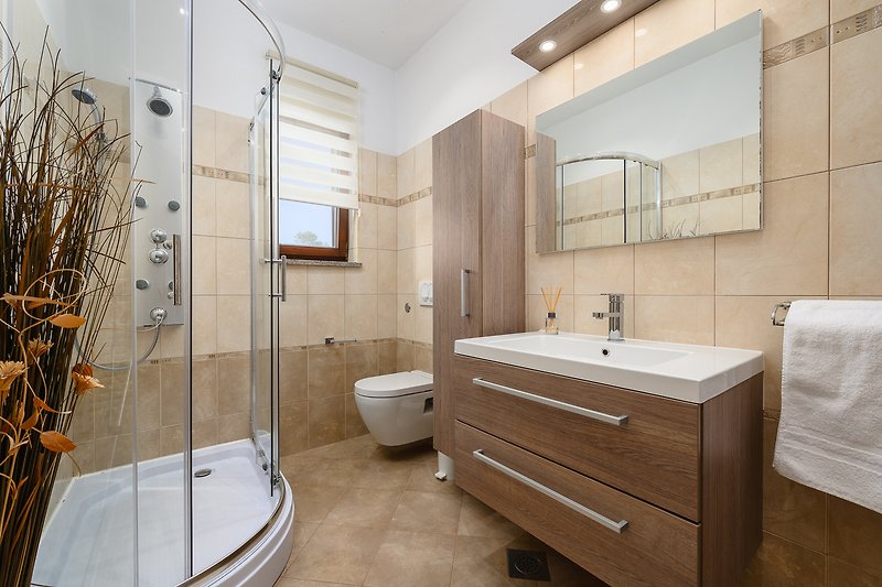 Predivna kupaonica s drvenim ormarićem, umivaonikom i tušem.