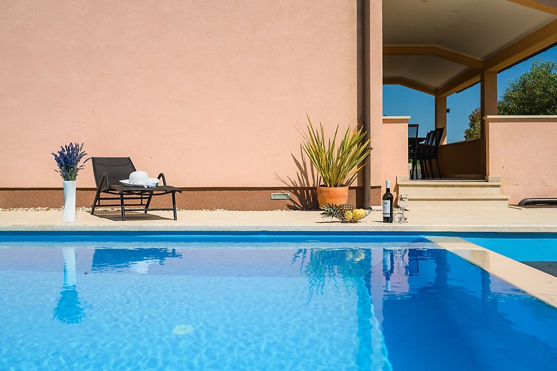 Predivan pogled na bazen s vanjskim namještajem i suncobranom u predivnom okruženju.