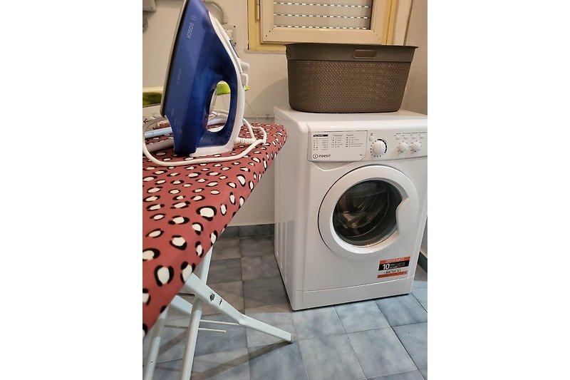 Waschraum mit Waschmaschine, Trockner und Kameraausrüstung.