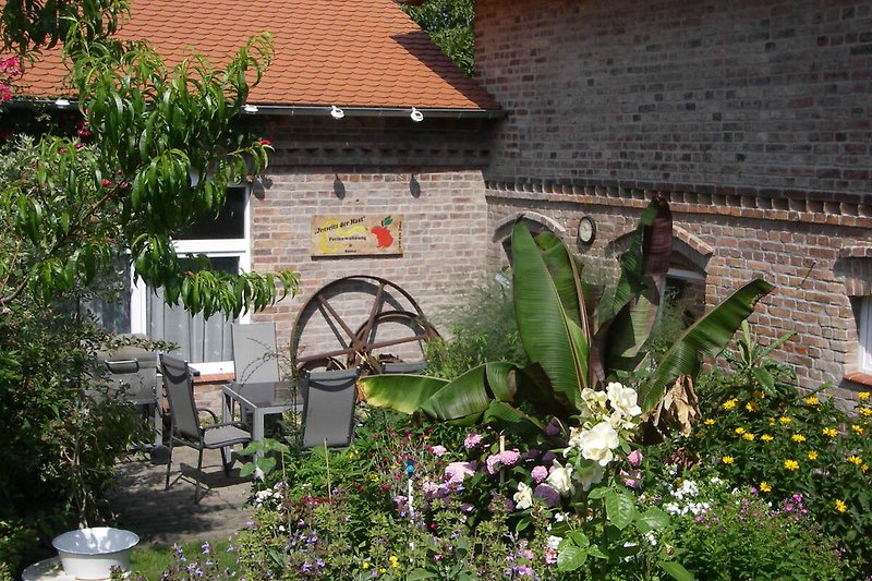 Ein malerischer Garten mit blühenden Pflanzen und einem gemütlichen Sitzplatz.