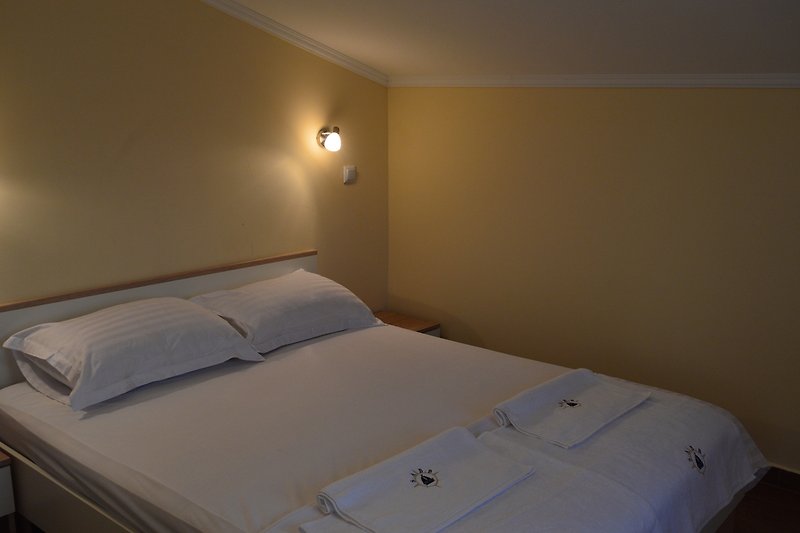 Elegantna spavaća soba s udobnim krevetom i svijetlim osvjetljenjem.