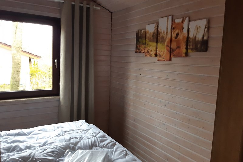 Schlafzimmer mit Holzbett, Kunst an der Wand und Pflanze.