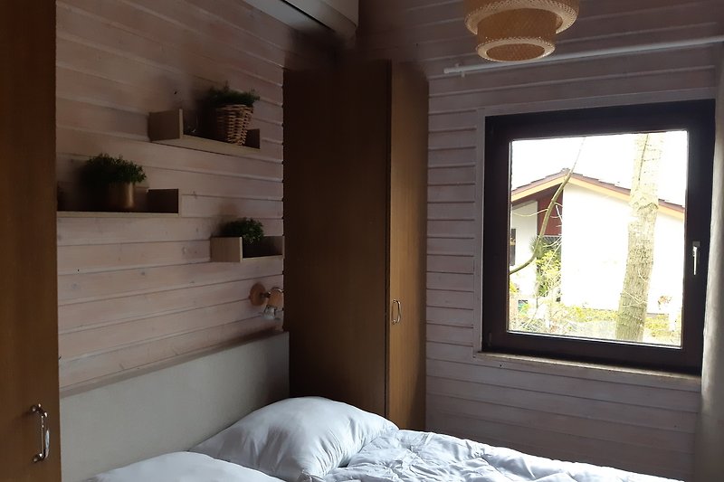 Lichtdurchflutetes Schlafzimmer mit Holzbett und Pflanze.