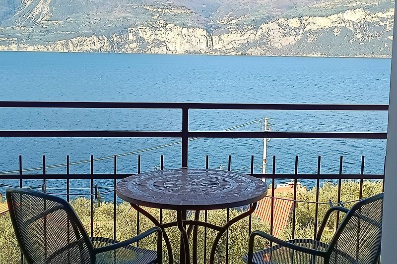 Blick auf See und Berge, mit Outdoor-Möbeln und Tisch.