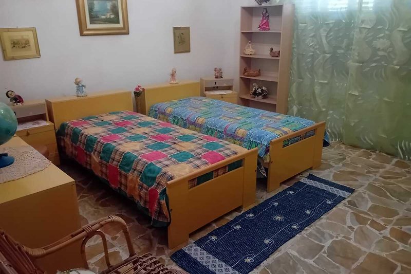 Gemütliches Schlafzimmer mit Holzmöbeln, Bettwäsche und Bilderrahmen.
