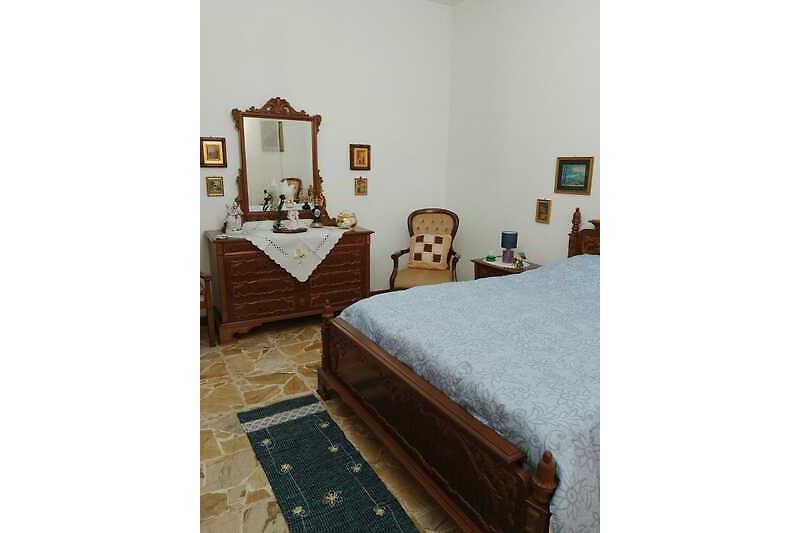 Gemütliches Schlafzimmer mit Holzmöbeln, Bett und Nachttisch.
