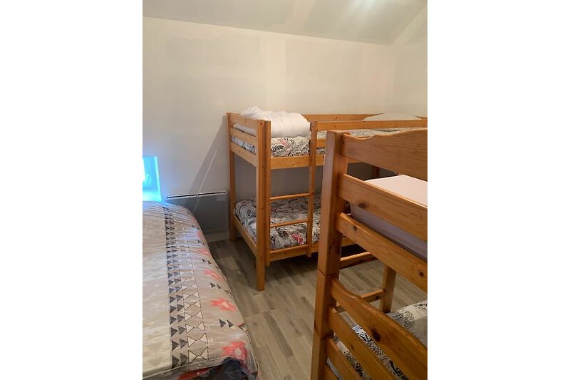 Kinder Schlafzimmer mit Etagenbett, Holzboden und gemütlicher Bettwäsche.