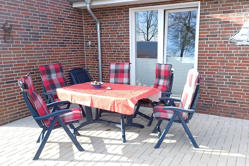 Gemütliche Terrasse mit Holzmöbeln und Tisch im Freien.
