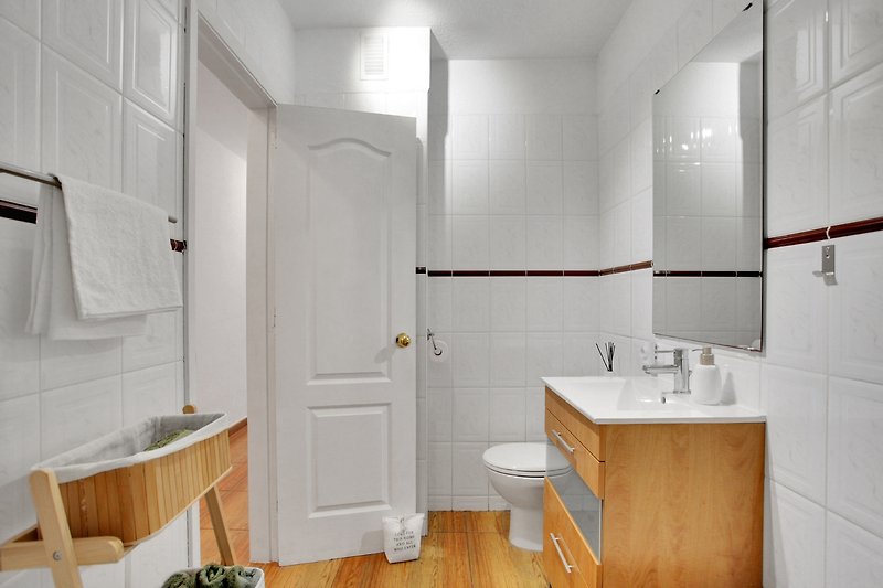 Badezimmer mit Holzdetails, Glasdusche und modernen Armaturen.