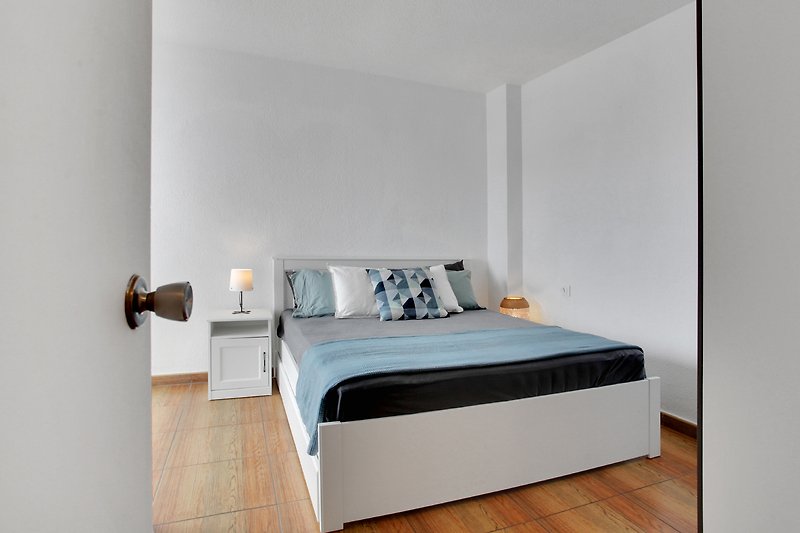 Modernes Schlafzimmer mit elegantem Bettgestell, Holzmöbeln und stilvoller Beleuchtung.