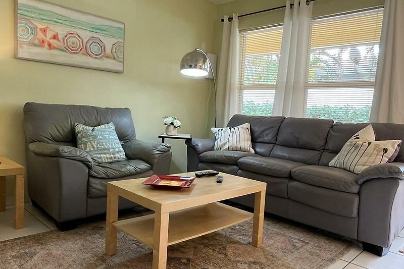 Stilvolles Wohnzimmer , gemütlicher Couch, Smart TV und moderner Kunst.