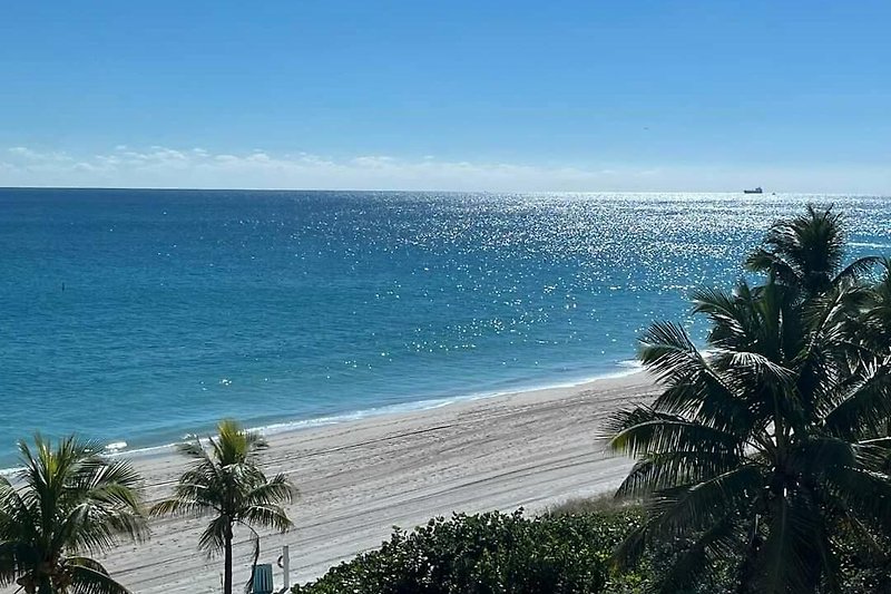Karibische Küstenlandschaft mit Palmen, Strand und Meer.