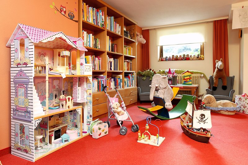 Kinderzimmer mit Spielzeug, Bücherregal und Pflanze.