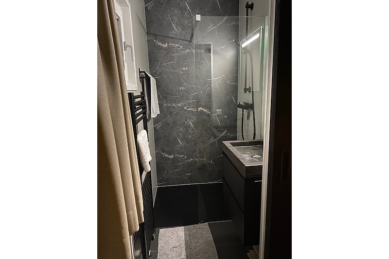 Modernes Badezimmer mit schwarzen Armaturen und Fliesen.