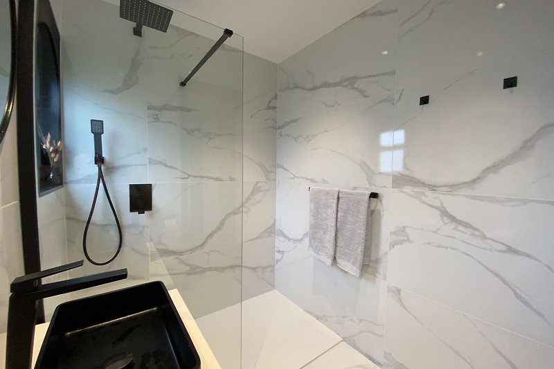 Moderne marmeren badkamer met vloerverwarming en regendouche