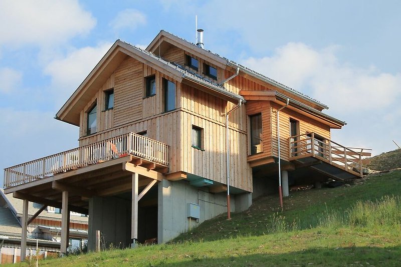 Blick auf Haus mit Holzfassade, Fenstern und Dach in den Bergen.