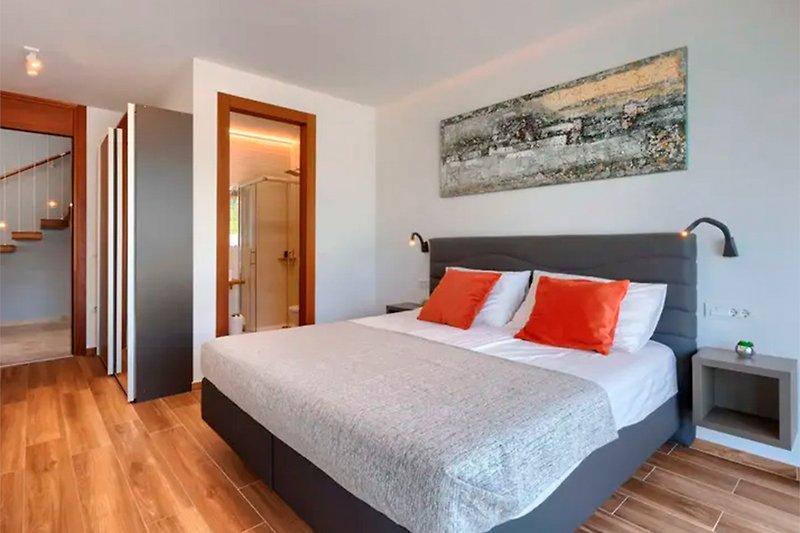 Elegant bedroom with hardwood bed frame, cozy bedding, and warm lighting.
