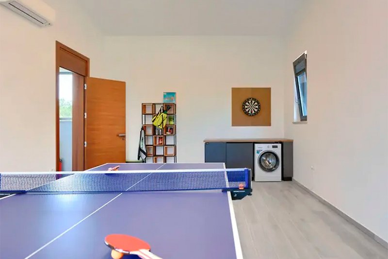 Modern recreation room with ping pong table, orange accents, and hardwood furniture.