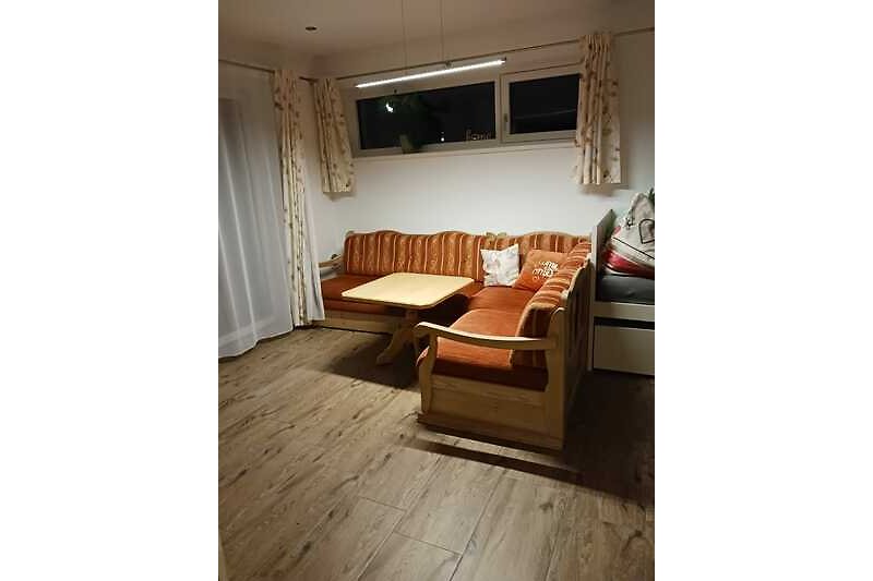 Wohnzimmer mit Holzmöbeln, bequemer Couch und Deckenlampe.