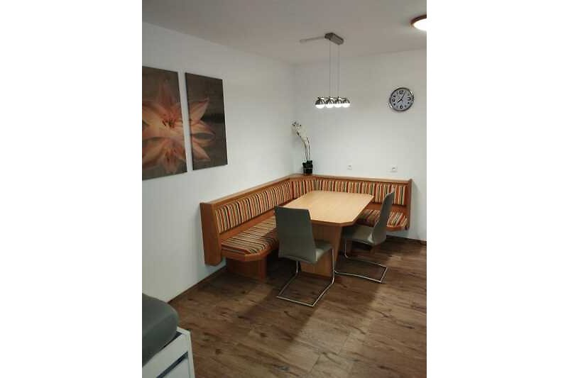 Wohnzimmer mit Holzmöbeln, Tisch, Stühlen und Deckenbeleuchtung.