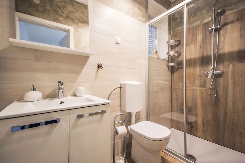 Luksuzna kupaonica s modernim tušem i elegantnim ormarićem.
