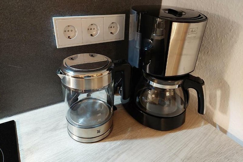Kaffeemaschine mit Aluminium-Design und Wasserkocher in der Küche.