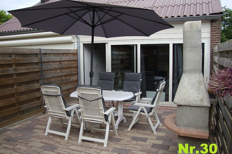 Ferienhaus mit stilvoller Einrichtung, Terrasse, Grillkamin Gartenmöbel und  Sonnenschirm.