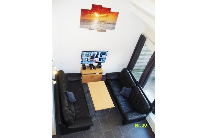Stilvolles Wohnzimmer mit bequemer Ledercouch, Tisch, TV und Musikanlage