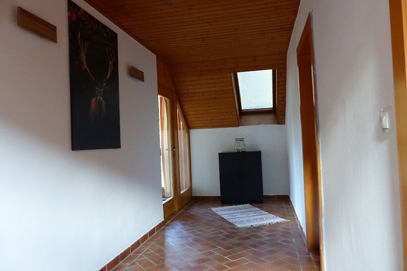 Geräumiger Wohnraum mit Holzinterieur und großen Fenstern.
