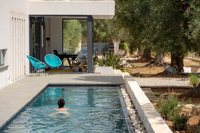 Tranquil poolside setting with outdoor furniture and lush landscaping.