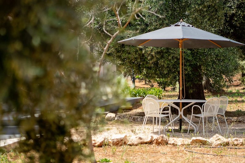 Relax under the shade of an umbrella in a lush garden setting.