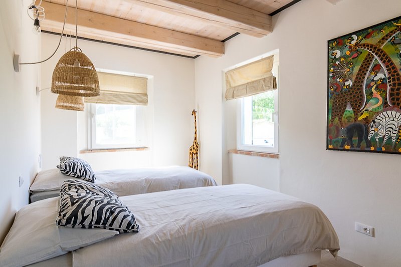Stylish bedroom with elegant bedding, wood flooring, and soft lighting.