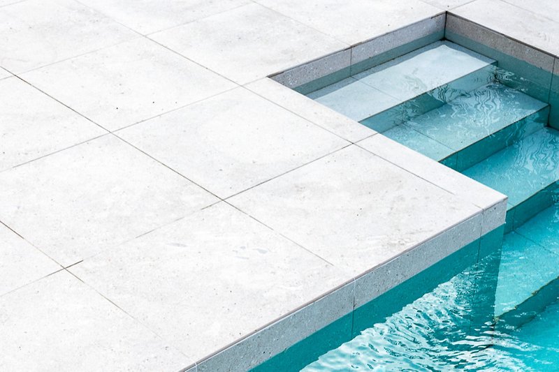 Stylish urban pool with glass facade and ocean view.