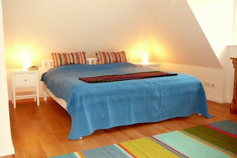 Modernes Schlafzimmer mit stilvollem Bett, Lampen und gemütlicher Einrichtung.