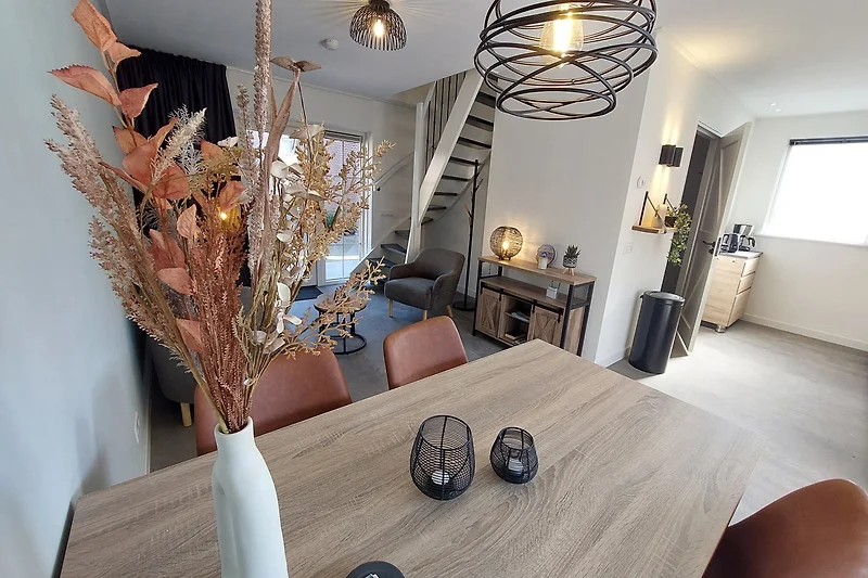 Eetkamer met houtdecor, kroonluchter en planten.