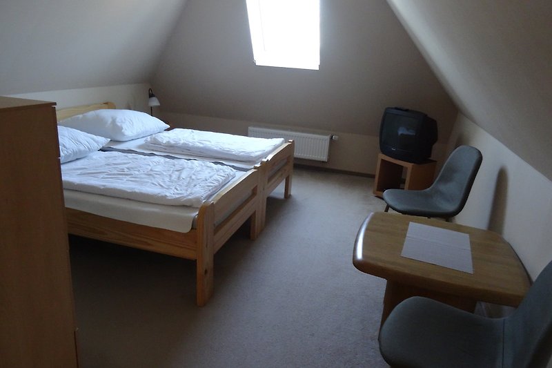 Schlafzimmer mit bequemem Bett, Holzmöbeln und Lampen.