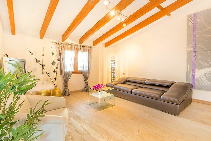 Wohnzimmer mit Holzmöbeln, Couch, Tisch und Lampen. Gemütliche Atmosphäre.