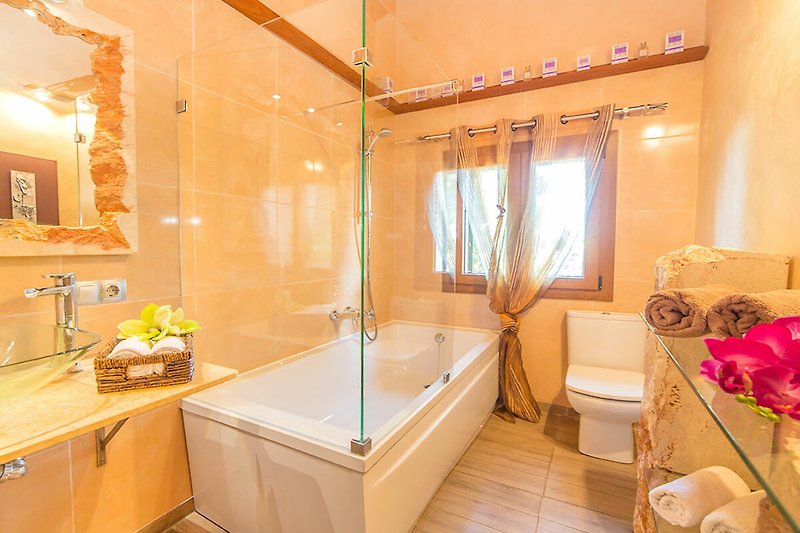 Badezimmer mit Badewanne, Dusche, Spiegel und Pflanze.