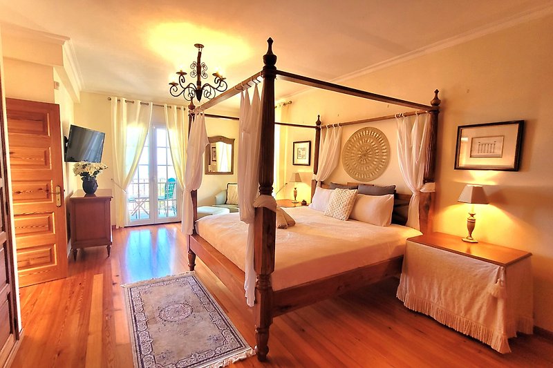 Elegantes Schlafzimmer mit Himmelbett und stilvoller Beleuchtung.