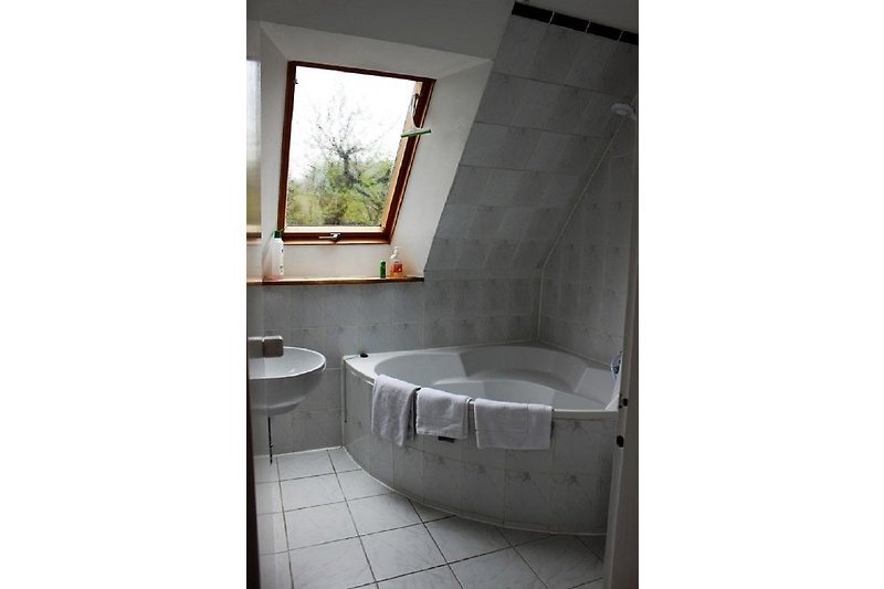 Badezimmer mit Badewanne, Fenster, Holz und Fliesen.